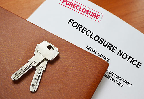 Official foreclosure notice document with house keys on a wooden table.